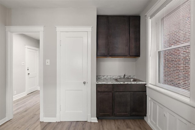 kitchen with sink, dark brown cabinets, and light wood-type flooring