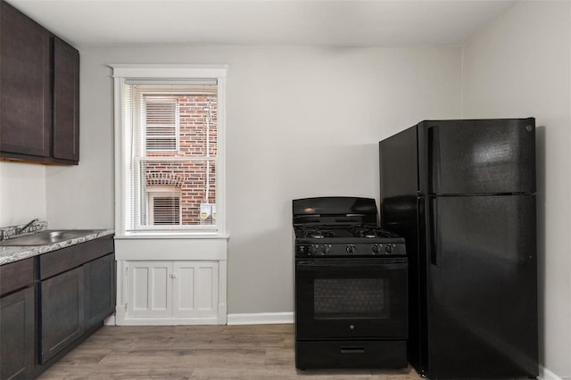 kitchen featuring sink, light wood-type flooring, black appliances, and dark brown cabinetry