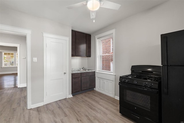 kitchen with sink, light wood-type flooring, black appliances, and dark brown cabinetry