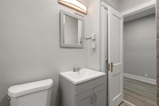 bathroom with toilet, hardwood / wood-style floors, and vanity