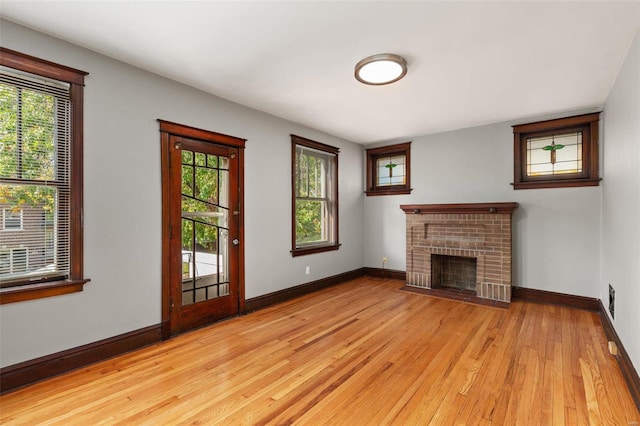 unfurnished living room featuring a fireplace, light wood-type flooring, and plenty of natural light