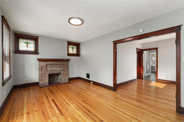 unfurnished living room featuring a fireplace, light wood-type flooring, and a wealth of natural light