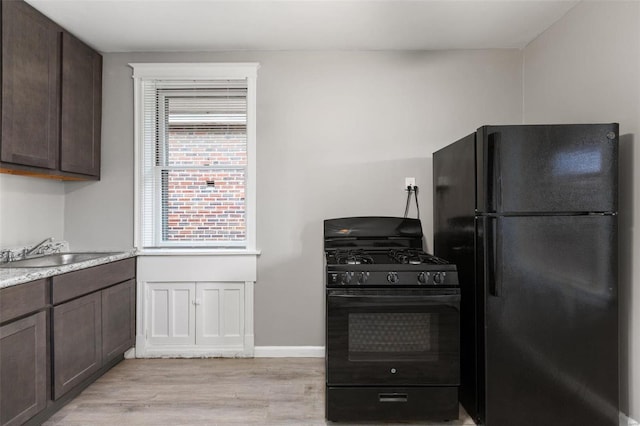 kitchen with light wood-type flooring, black appliances, dark brown cabinets, and sink