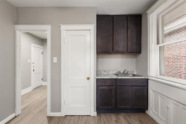 kitchen with sink, light wood-type flooring, and dark brown cabinetry