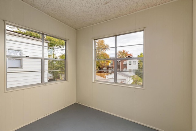 unfurnished room with a textured ceiling and wood walls