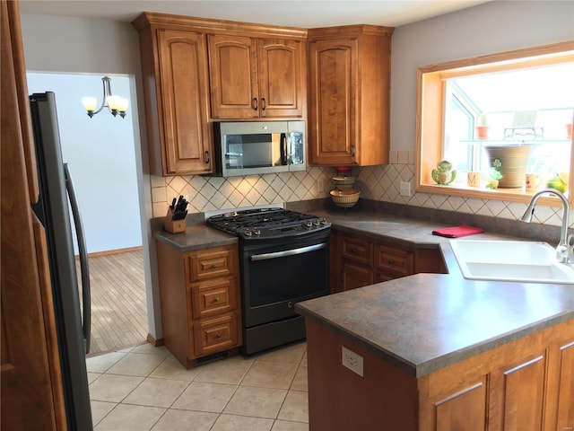 kitchen with light tile patterned floors, an inviting chandelier, backsplash, appliances with stainless steel finishes, and sink