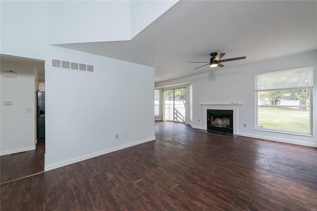 unfurnished living room featuring a high end fireplace, ceiling fan, and dark wood-type flooring