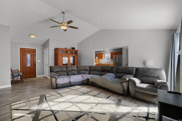 living room with ceiling fan, hardwood / wood-style flooring, and vaulted ceiling