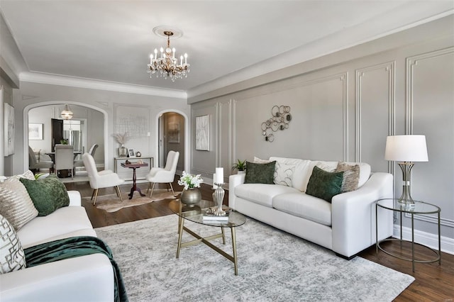 living room with crown molding, dark wood-type flooring, and an inviting chandelier