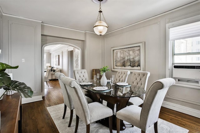 dining area with arched walkways, wood finished floors, and ornamental molding