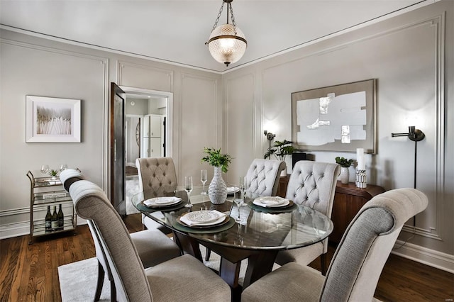 dining space featuring a decorative wall and wood finished floors