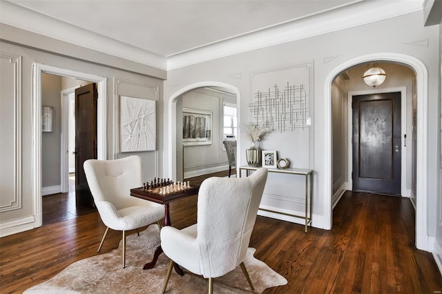 foyer entrance with baseboards, arched walkways, and wood finished floors