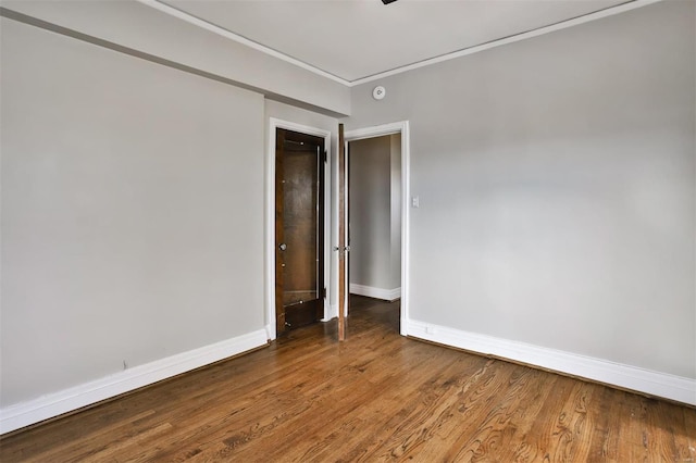 unfurnished room with baseboards, wood finished floors, and ornamental molding