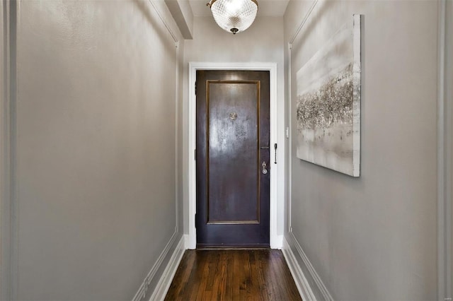 doorway with dark wood-type flooring and baseboards