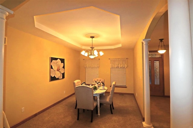 carpeted dining space with an inviting chandelier, a raised ceiling, and decorative columns