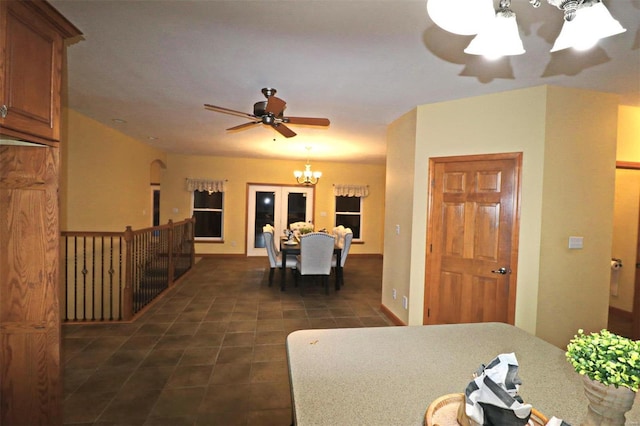 dining room featuring ceiling fan with notable chandelier and dark tile patterned flooring