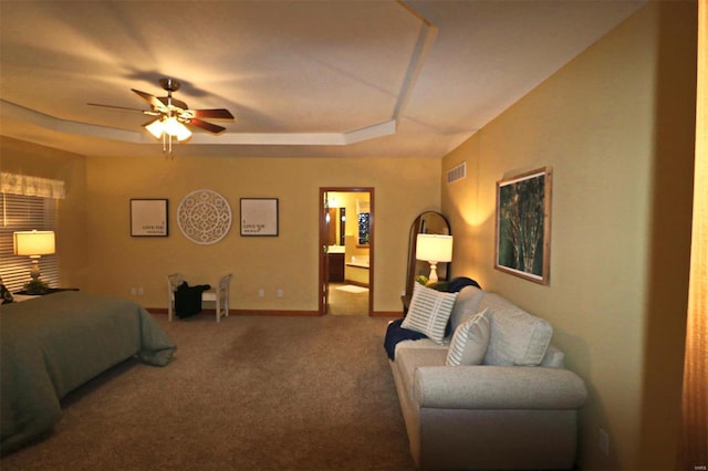 carpeted bedroom with a raised ceiling and ceiling fan