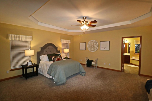 carpeted bedroom featuring a raised ceiling, ceiling fan, and ensuite bathroom