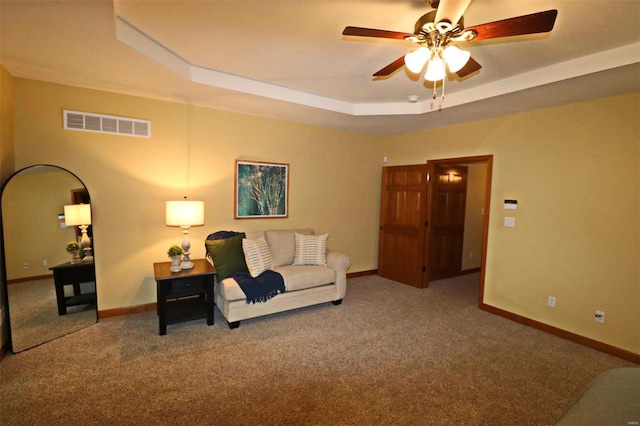 carpeted living room featuring ceiling fan and a tray ceiling