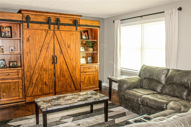 living room with a barn door and dark hardwood / wood-style floors