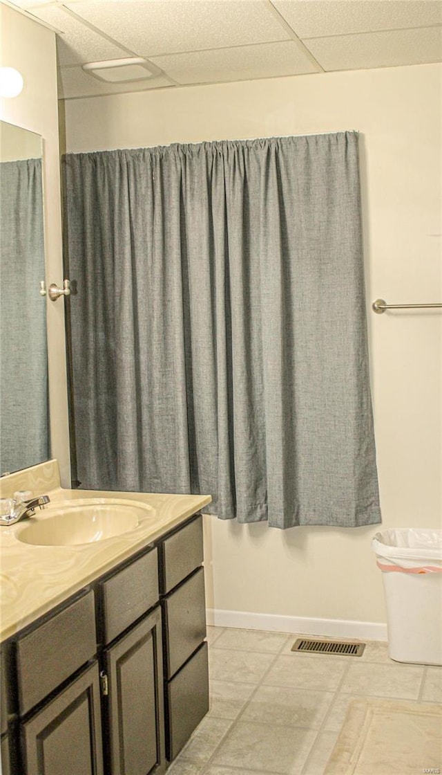 bathroom featuring a paneled ceiling and vanity