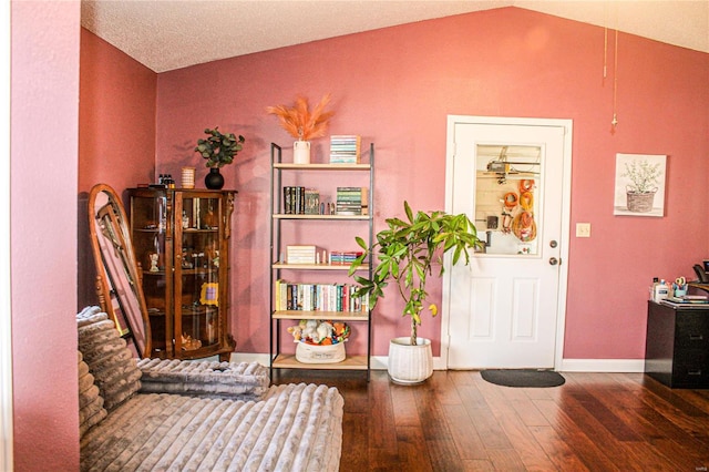 sitting room with hardwood / wood-style flooring, vaulted ceiling, and a textured ceiling