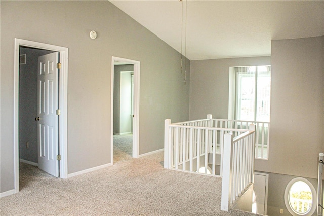 corridor with vaulted ceiling and light colored carpet