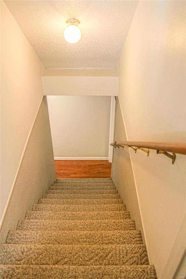 staircase with hardwood / wood-style flooring and a textured ceiling