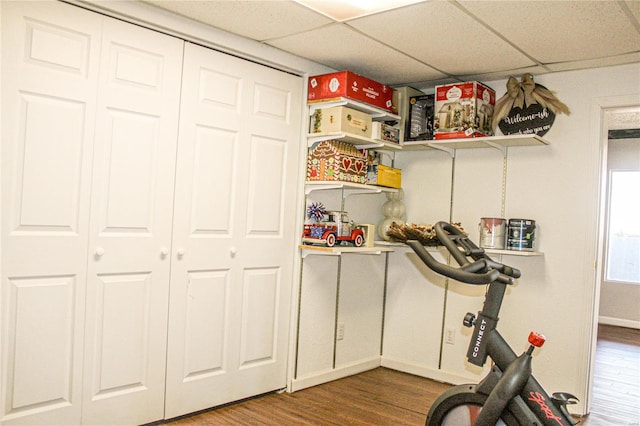 exercise room with a paneled ceiling and hardwood / wood-style floors