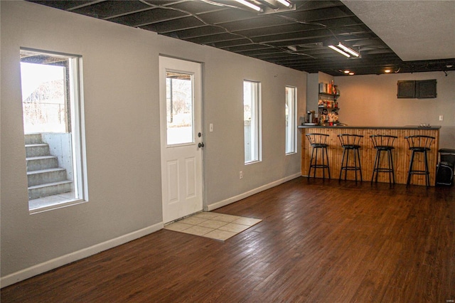 foyer entrance with hardwood / wood-style flooring and bar