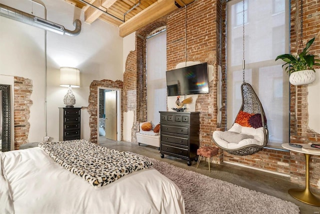 bedroom with beam ceiling, a towering ceiling, and brick wall