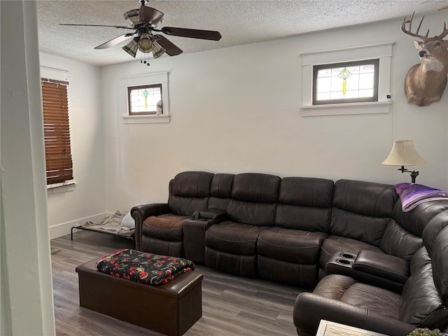 living room with a textured ceiling, ceiling fan, and dark hardwood / wood-style floors