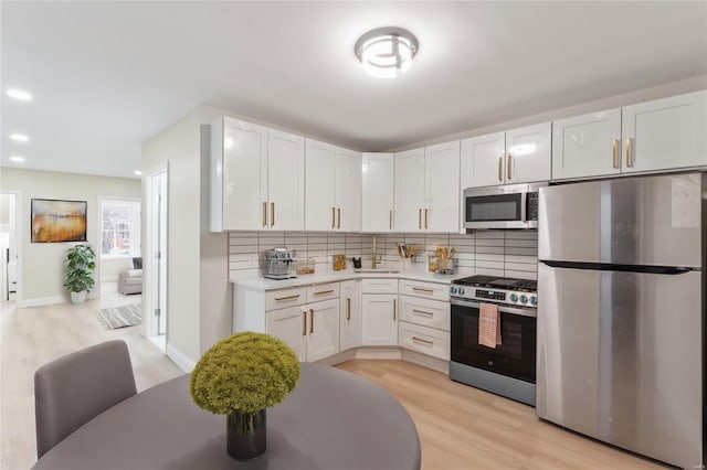 kitchen featuring stainless steel appliances, light hardwood / wood-style floors, decorative backsplash, and white cabinets