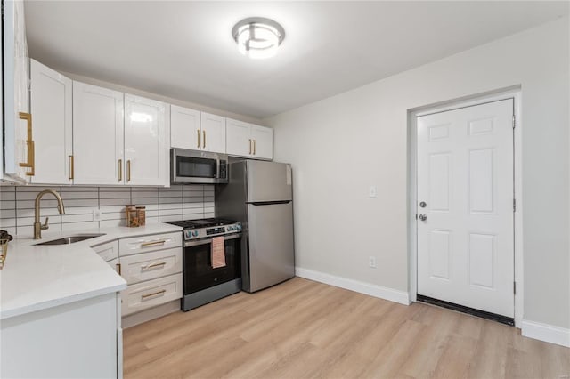 kitchen with white cabinetry, stainless steel appliances, sink, and decorative backsplash