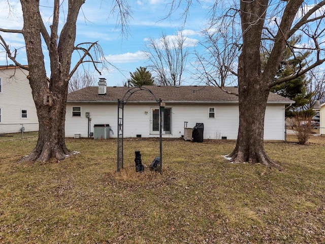 rear view of property featuring central AC unit and a lawn