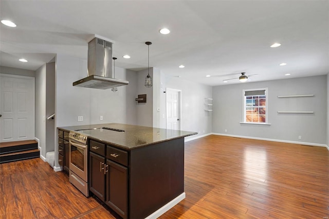 kitchen featuring electric stove, pendant lighting, dark brown cabinets, island range hood, and dark stone counters