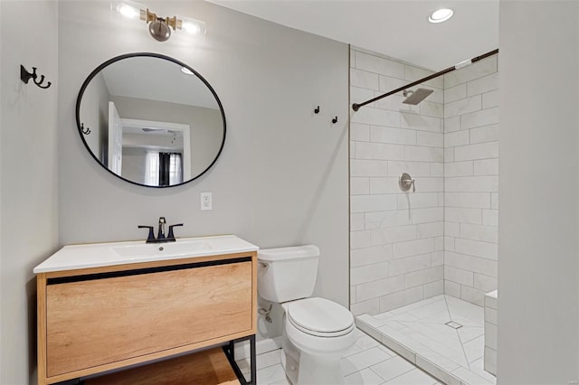 bathroom with tile patterned flooring, vanity, toilet, and a tile shower