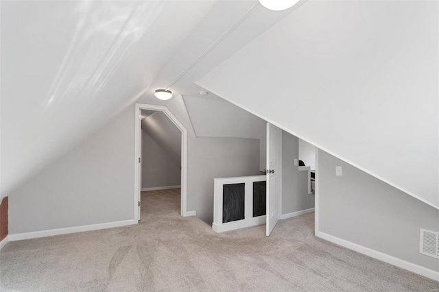 additional living space featuring light carpet and vaulted ceiling