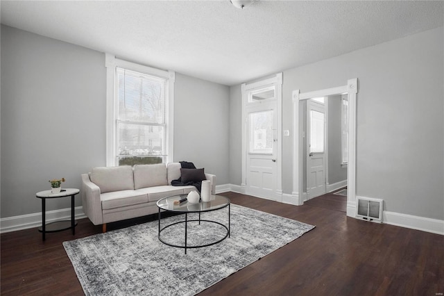 living room featuring a textured ceiling, dark hardwood / wood-style floors, and plenty of natural light