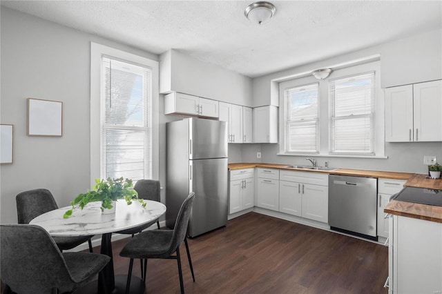 kitchen featuring stainless steel appliances, dark hardwood / wood-style flooring, butcher block countertops, white cabinets, and sink