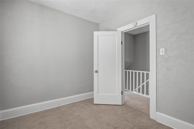 empty room featuring a textured ceiling and light carpet