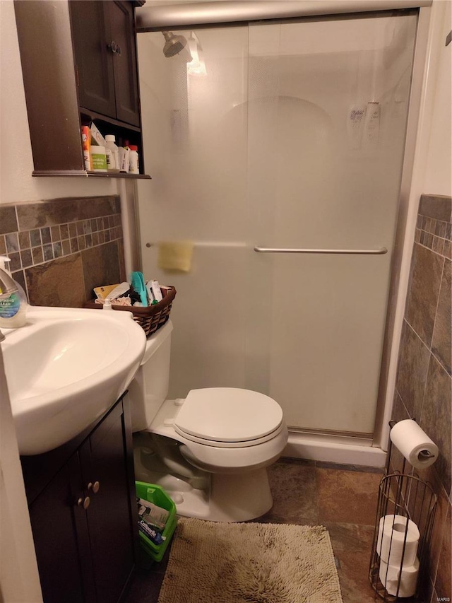 bathroom with tile walls, an enclosed shower, toilet, and vanity