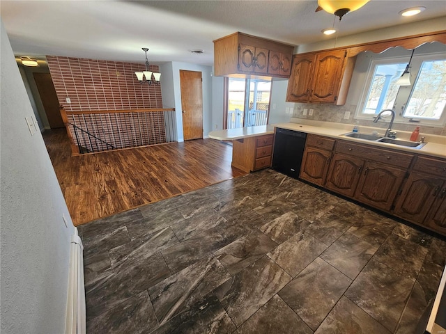 kitchen featuring dishwasher, kitchen peninsula, a healthy amount of sunlight, sink, and decorative light fixtures