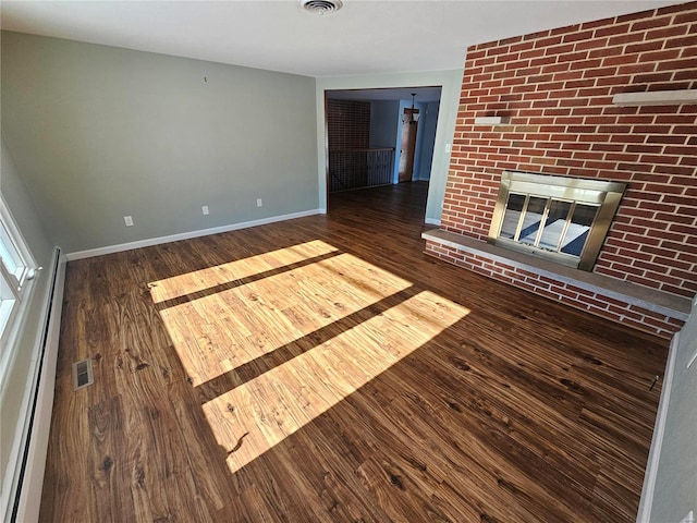 unfurnished living room featuring dark wood-type flooring, a baseboard radiator, and a fireplace