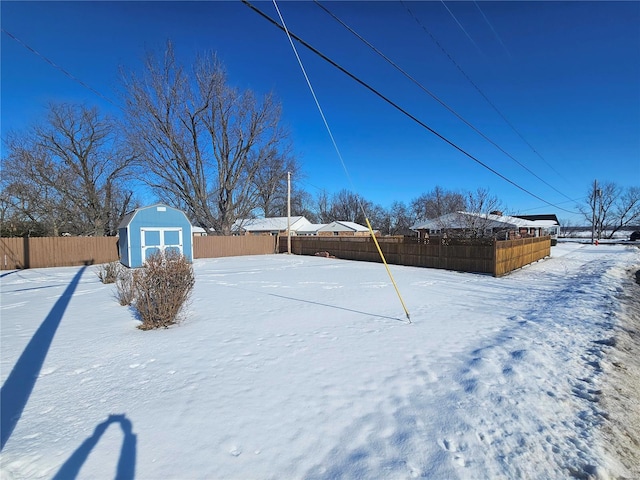 yard layered in snow featuring a storage shed