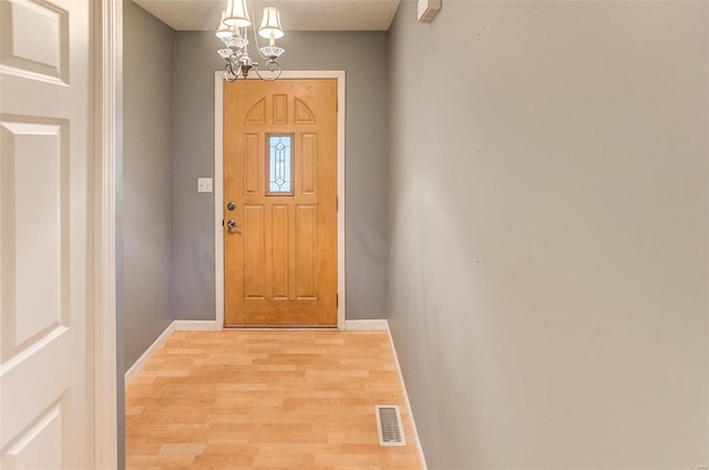 doorway to outside with a chandelier and light hardwood / wood-style flooring