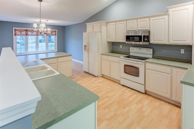 kitchen with pendant lighting, sink, white appliances, and light hardwood / wood-style floors