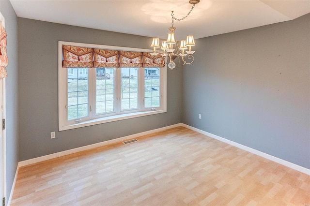 unfurnished room featuring hardwood / wood-style flooring and an inviting chandelier