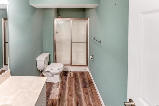 bathroom with an enclosed shower, hardwood / wood-style floors, vanity, and toilet