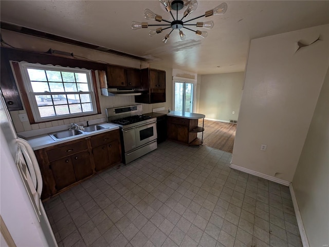 kitchen with dark brown cabinetry, a chandelier, double oven range, and sink